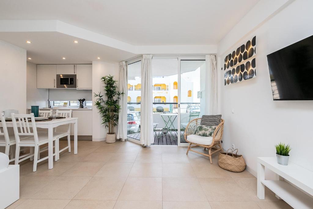 White open-plan living area with dining space and doors to the balcony