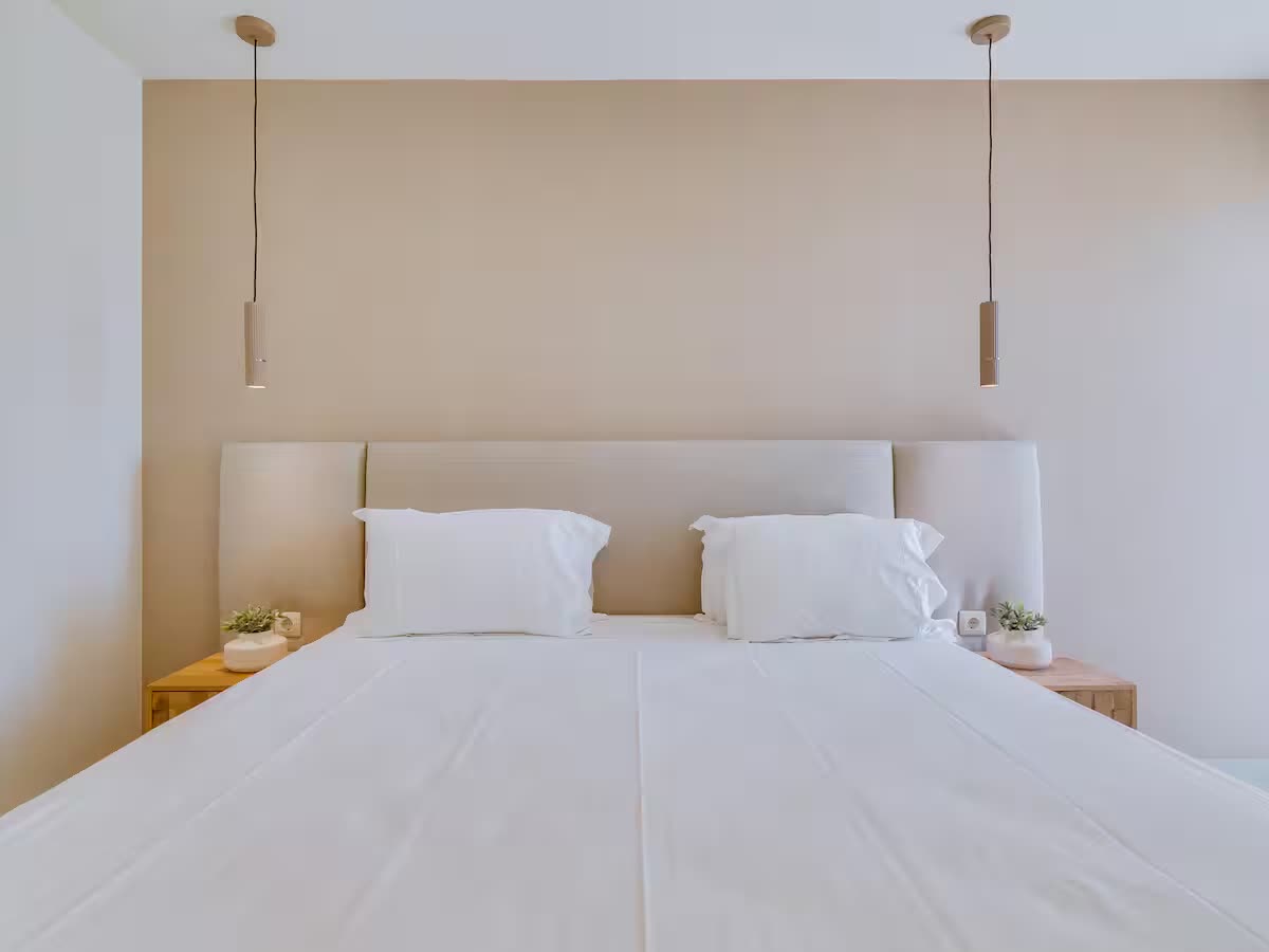 Bright second bedroom with an upholstered headboard and pendant lights